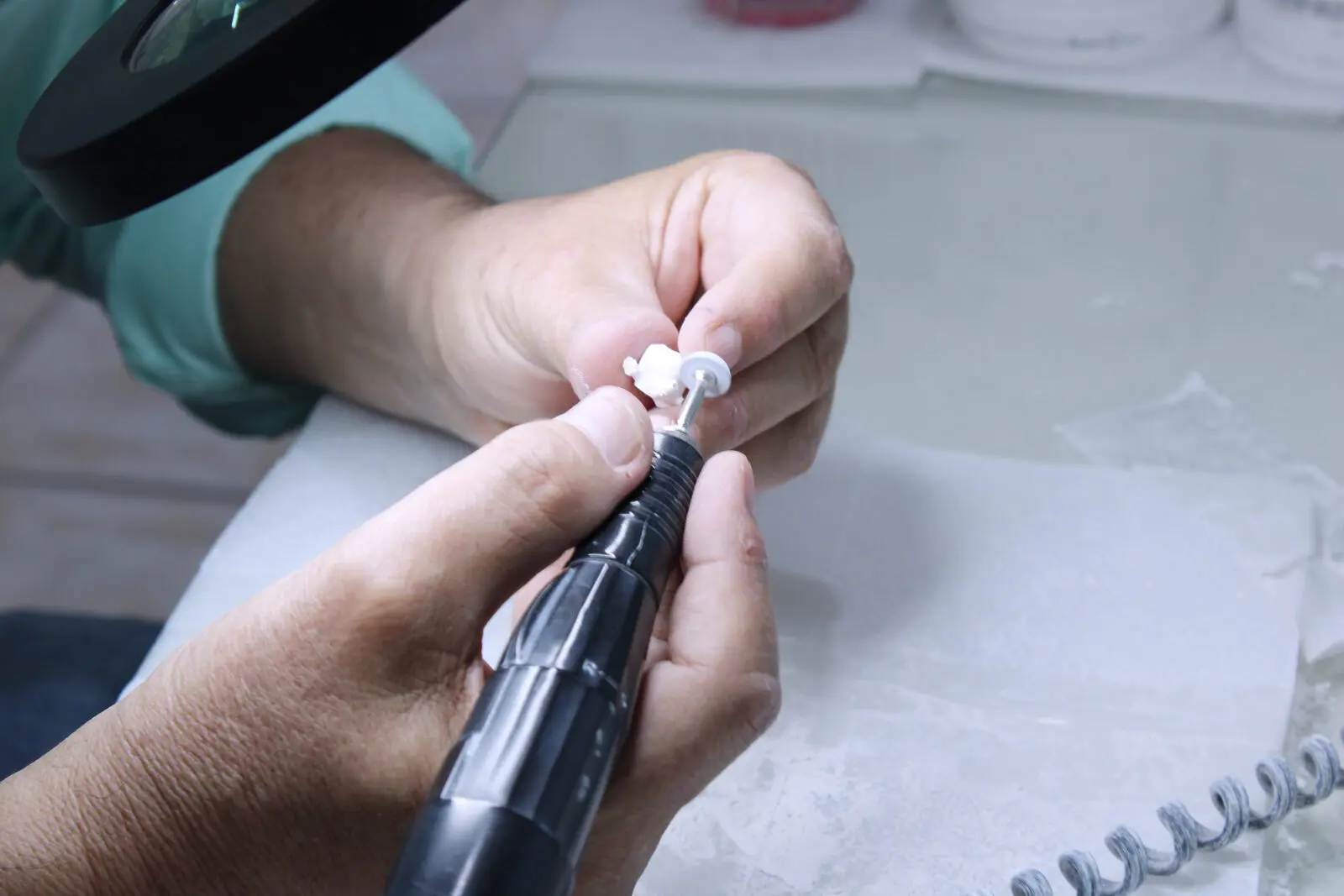 Acabado manual de una corona dental bajo lupa con micromotor