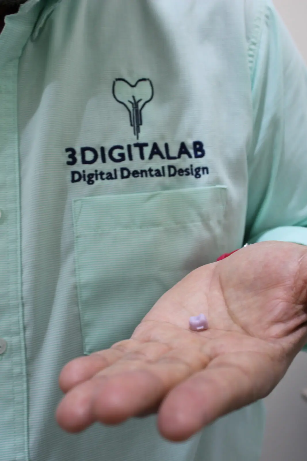 Corona de zirconia presinterizada en la mano de un técnico de 3DigitaLab