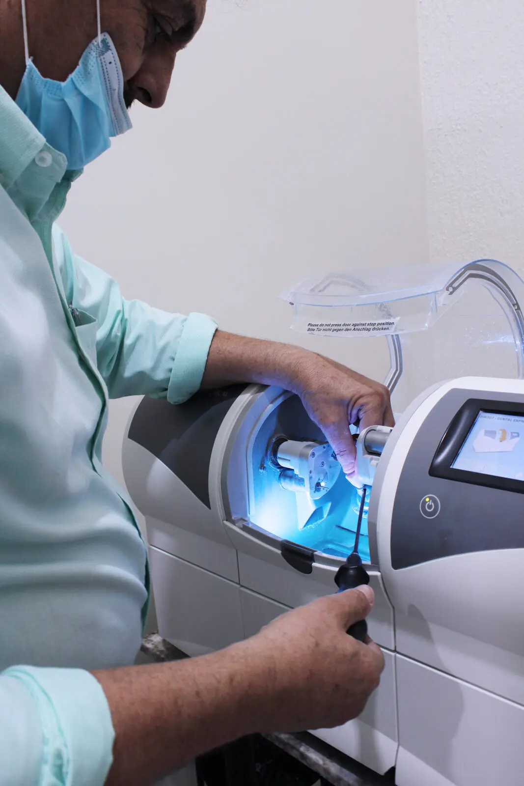 Técnico ajustando la fresadora CAD/CAM del laboratorio dental